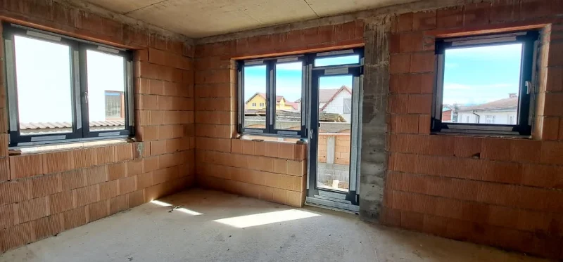 Încăpere cu ferestre și o ușă de balcon cu ramă antracit, văzute din interior