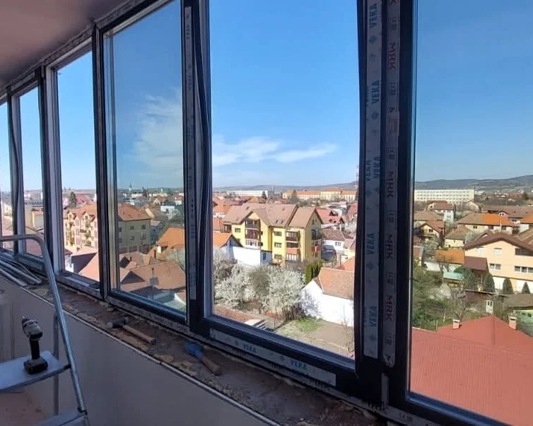 Ferestre înalte cu ramă antracit, montate într-o încăpere, cu vedere spre oraș