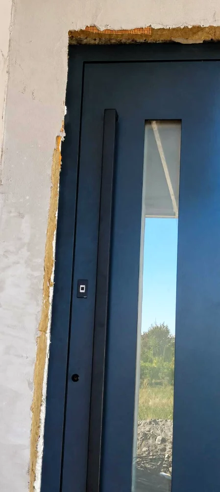 Detaliu al unei uși de intrare antracit cu sticlă verticală și deschidere cu amprentă