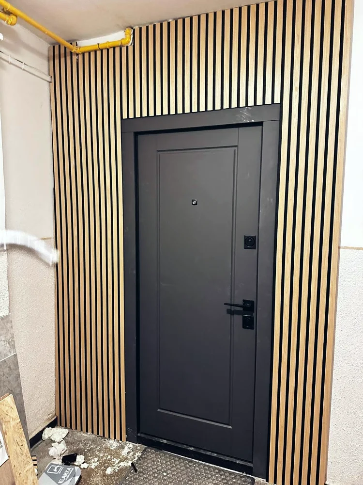 Ușă de acces apartament, antracit, lângă un perete placat cu riflaj din lemn