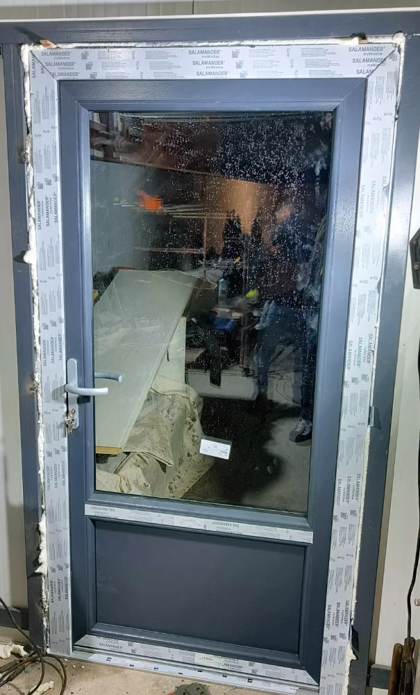 Ușă antracit cu geam mare, încă protejată cu folie, în timpul montajului