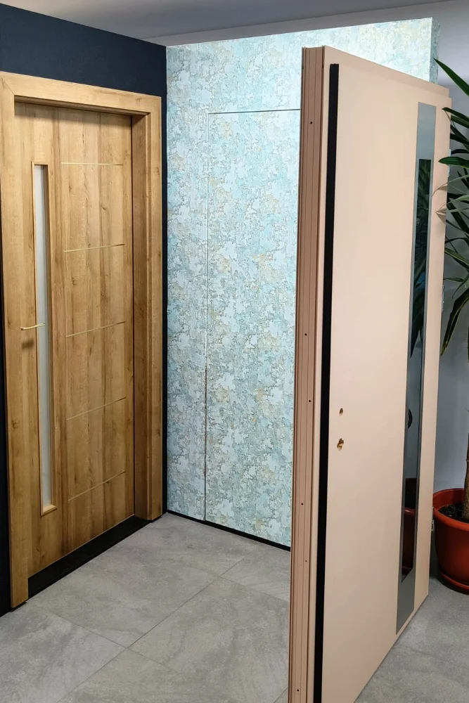 Ușă cu decor lemn și o ușă roz-piersică deschisă, pe același hol