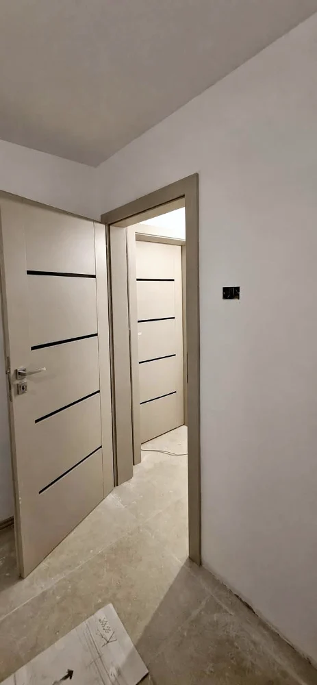 Ușă de interior albă cu dungi orizontale negre, pe un hol