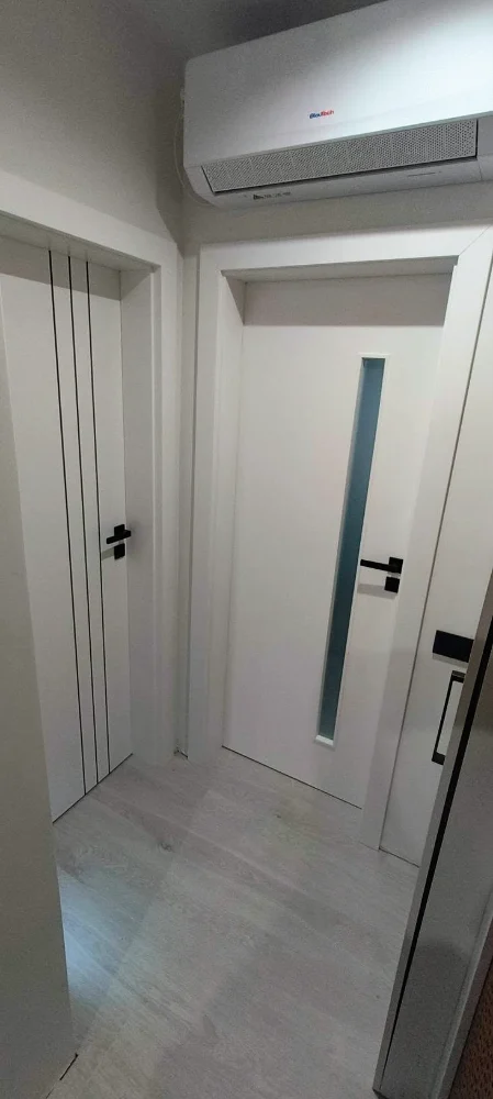 Uși de interior albe, una cu fantă verticală de sticlă