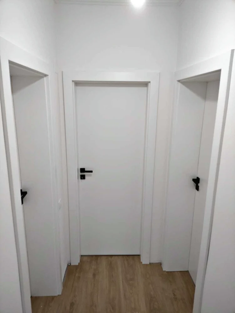 Uși de interior albe cu mânere negre, pe un hol