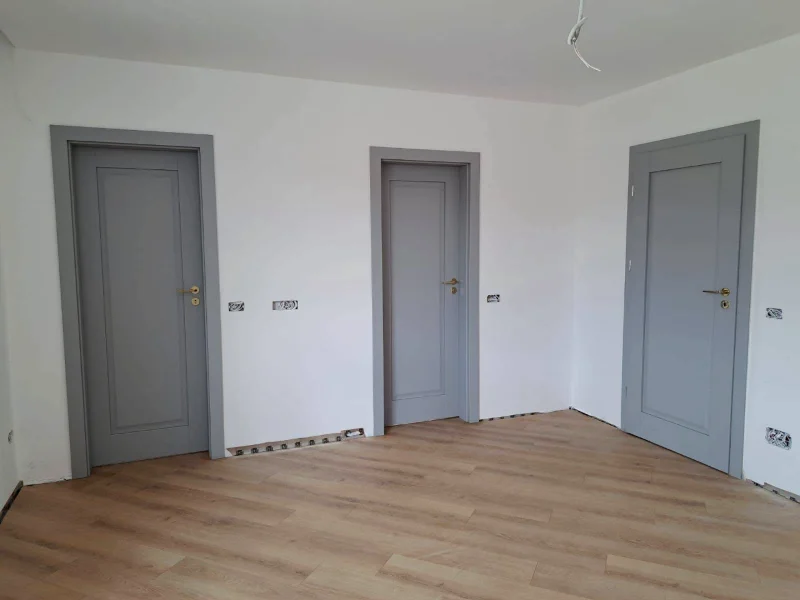 Trei uși de interior gri cu panou clasic, într-o cameră cu parchet