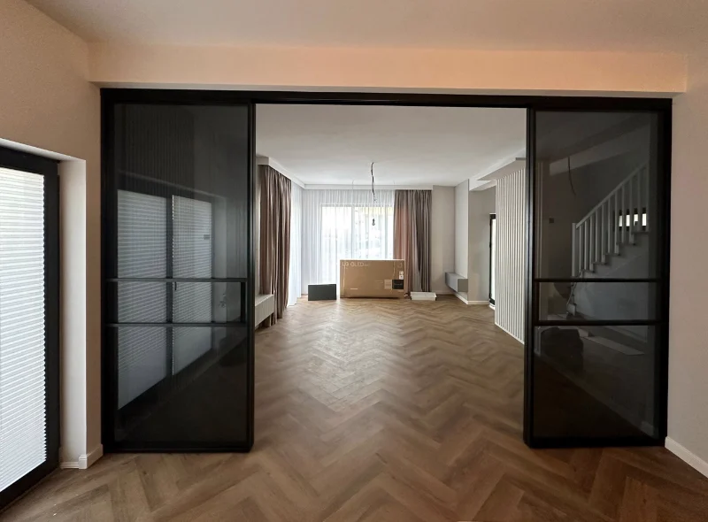 Separeu din aluminiu negru într-un living cu parchet în spic